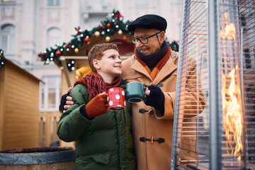 Canvas Print - Happy grandfather and grandson toasting while drinking tea at Christmas market during winter day.