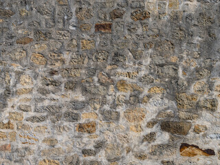 Old stone wall texture with different natural stones. Abstract background from a building exterior. Weathered rough masonry pattern of the material. Vintage architecture in a rural area.