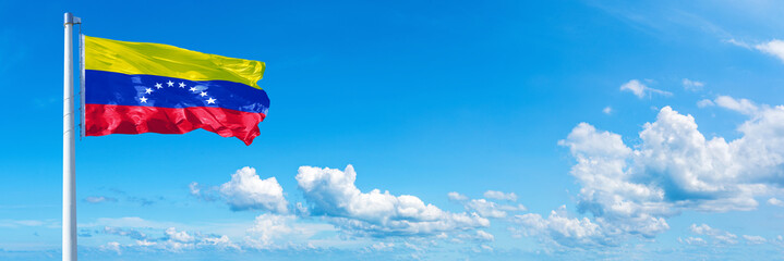 Wall Mural - Venezuela flag waving on a blue sky in beautiful clouds - Horizontal banner