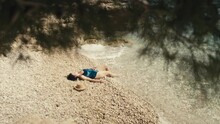 A Girl Is Sunbathing Lying On The Beach In A Swimsuit Alone. A Woman On Vacation By The Ocean Relaxes At A Luxury Resort. High Quality 4k Footage