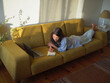© ZHPH Production/Stocksy - Woman with laptop and notebook sitting on the sofa at home