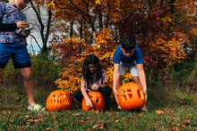 Kids Leaning Down To Pickup Oversized Pumpkins. 