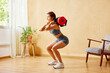 © ALTO IMAGES/Stocksy - Sportswoman squatting with sandbag at home