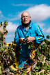 © Ezequiel Giménez/Stocksy - Aged farmer standing behind grapevine
