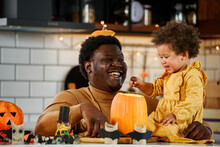 Father And Cute Little Daughter Having Fun With Jack -o -lantern In The Kitchen. Halloween Holiday