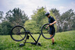 © Daniel Gonzalez/Stocksy - Male cyclist fixing bike in field