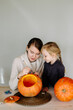 © Sergey Narevskih/Stocksy - Mother with daughter drawing ornament on pumpkin