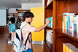 © Santi Nuñez/Stocksy - Student taking a book in a library