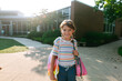 © Maria Manco/Stocksy - Young girl smiles at the camera in front of her school