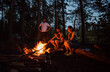 © Duet Postscriptum/Stocksy - Friends near bonfire in camping zone in the forest.