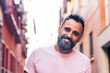 © Pedro Merino/Stocksy - Portrait of a man with a gray beard smiling on the street