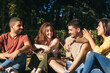 © Pedro Merino/Stocksy - Group of friends sitting in a park talking and enjoying together