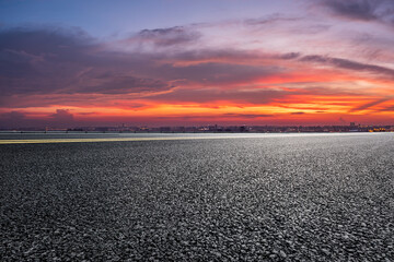 Asphalt road and modern city skyline scenery at sunset