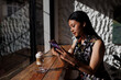 © Saptak Ganguly/Stocksy - Young woman enjoying coffee and browsing on smartphone inside a cafe