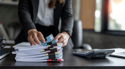 Businesswoman hands working in Stacks of paper files for searching and checking unfinished document achieves on folders papers