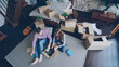 © silverkblack - Top view of happy young couple unpacking things, opening carton box, taking things and talking after moving to new apartment. Relationship and relocation concept.