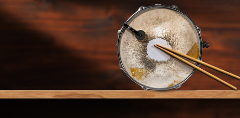 Wall Mural - Two wooden drumsticks and an old metallic snare drum, above a wooden shelf with copy space. Percussion instrument. Photography.