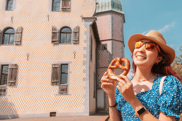 Wall Mural - Happy girl tourist eating traditional pretzel snack on the background of the Ledenhof building in Osnabruck, Germany