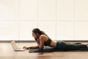 Happy senior woman joining an online yoga class on a laptop