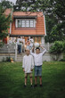 © Maskot - Playful boys with soccer ball standing in back yard with family on porch in background