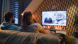 © Framestock - Couple sitting on sofa with snacks in living room, watching news on TV channel about astronauts, space mission, exploring Earth orbit. Wife and husband resting and chilling at home on weekend at night