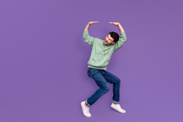 Wall Mural - Full body photo of attractive young man lifting heavy falling ceiling dressed stylish khaki garment isolated on purple color background