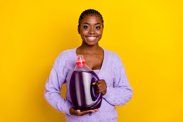 Wall Mural - Portrait of positive nice lady arms hold demonstrate laundry detergent bottle isolated on yellow color background