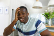 © WavebreakMediaMicro - Happy african american man making video call smiling to camera holding head in kitchen
