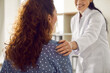 Doctor supporting her patient. Cropped shot of a happy, smiling nurse or doctor in white coat holding her hand on a woman's shoulder. Concept of medicine, healthcare, and female health