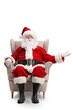 © Ljupco Smokovski - Santa claus sitting in armchair and showing at something with hand