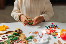 Child Hands Creating Christmas Crafts. Child Playing With Play Dough And Christmas Decorations. Holiday Art Activity For Kids. Sensory Play For Toddlers.