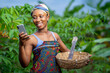 beautiful image of african lady, with smart phone and basket in a farm-black woman surfing on social media-agricultural concept