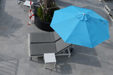  Blue umbrellas and gray sunbeds by the sea for tourists.