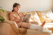 Girl with a cast on their leg, sitting on the couch and drawing on a graphics tablet. Bandaged leg cast and toes after a running injury accident.Teen girl in a plaster cast.