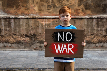 Wall Mural - Sad boy holding poster with words No War outdoors. Space for text