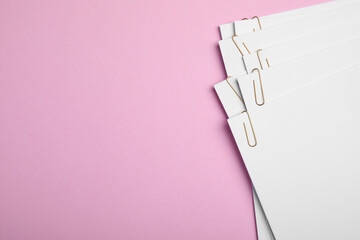 Sticker - Sheets of paper with clips on pink background, top view. Space for text