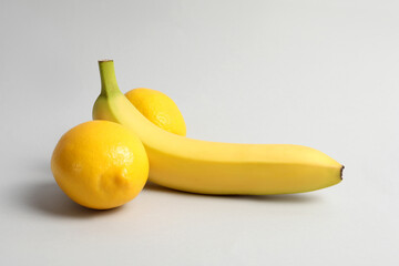 Wall Mural - Banana and lemons symbolizing male genitals on light grey background. Potency concept