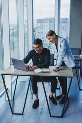 Wall Mural - Multiethnic executive team discussing financial report while sitting at table in office. Diverse business people, businessmen planning to work together in a meeting room using a laptop computer.