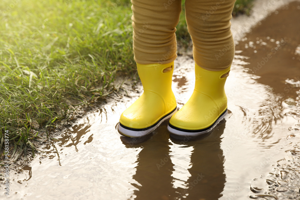 Little girl wearing rubber boots standing in puddle, closeup Stock ...