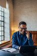 © bnenin - Smiling adult man with his glasses on, working over the laptop, making a phone call.