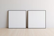 © Washdog - Two square blank picture canvases with thin black borders standing on wooden floor. Template for your content. 3D illustration.