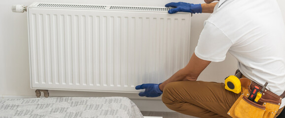 Portrait Of Mid-adult Male Plumber Repairing Radiator With Wrench.