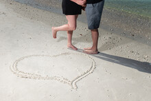 Romantic Shape In Sand With Lighting On The Heart While Couple Are In Kissing Position With Feet Facing Each Other