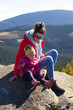 parent with child on rock on mountain top with forest and hills landscape view
