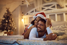 Young Happy Couple Relaxing On Bed On Christmas Eve At Home.