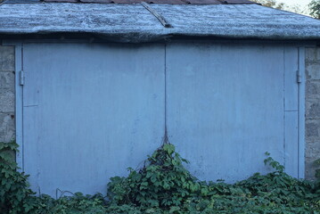 Sticker - one facade of a private garage with gray closed metal gates on the street in green grass