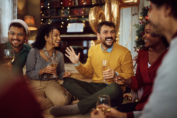 Wall Mural - Cheerful man has fun while drinking wine with his friends on New Year's party at home.