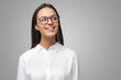 © Damir Khabirov - Female in white shirt and eyeglasses looking aside with dreamful expression isolated on gray