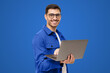 © Damir Khabirov - Portrait of modern business man standing in casual blue shirt, holding laptop and looking at camera