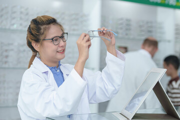 Wall Mural - Female ophthalmologist holding eyeglasses and examining them, focus on eyeglasses, close-up